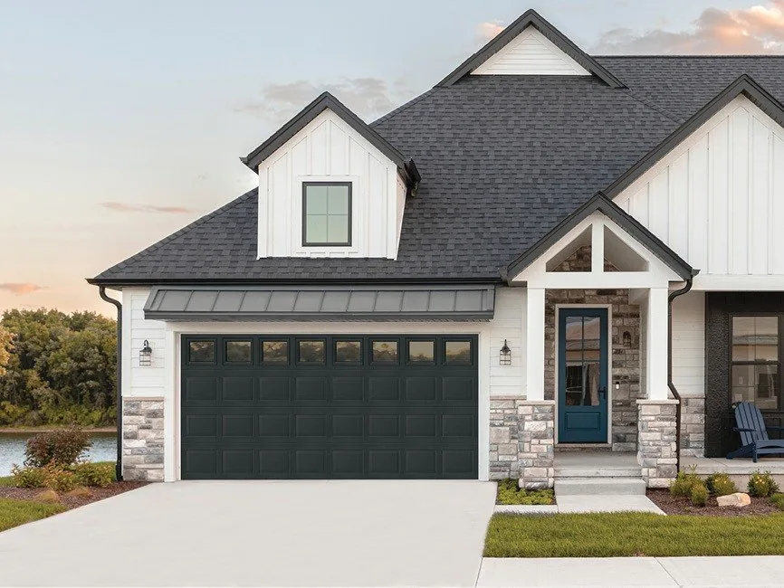 Modern home with a dark carriage-style insulated steel garage door with windows